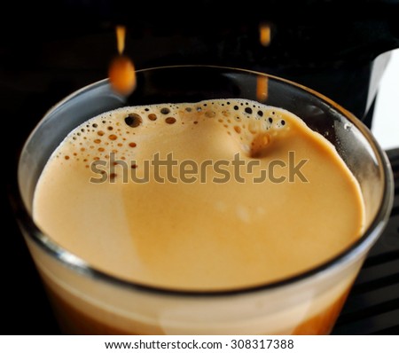 Close-up of fresh espresso coffee, pouring from coffee machine. (Selective shallow focus)