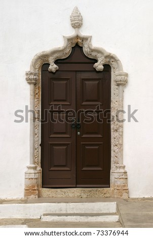 Portugal, Algarve, Alvor - beautiful intricately sculpted stone Manueline - Baroque door arch and wooden door - church facade