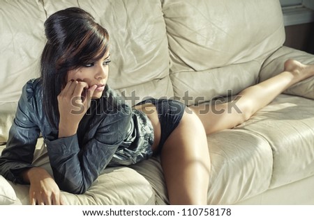 Beautiful seductive exotic young woman lying on couch