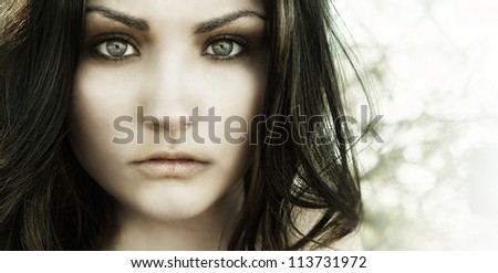 Close up photo of beautiful young woman\'s face with big eyes and vacant eerie stare.