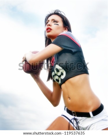 Beautiful young woman in American Football shirt and shorts running with ball.