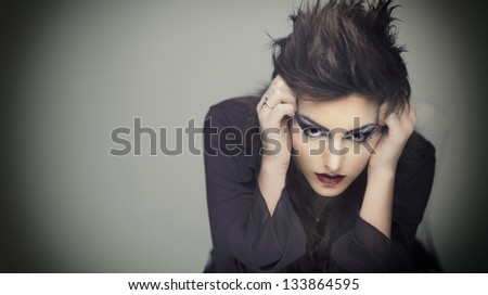 Portrait of young woman with hands on head in deep thought.