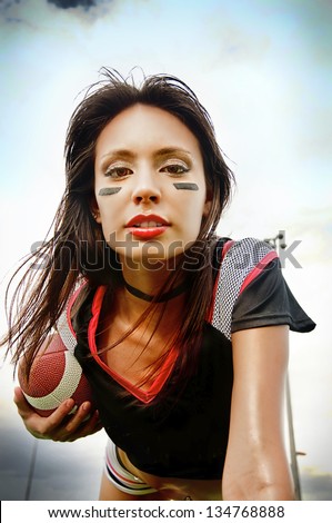 Beautiful young woman wearing American Football attire holding ball ready for action