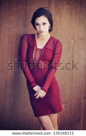 Fashion style portrait of beautiful young woman in red dress, slight grain added for styling.