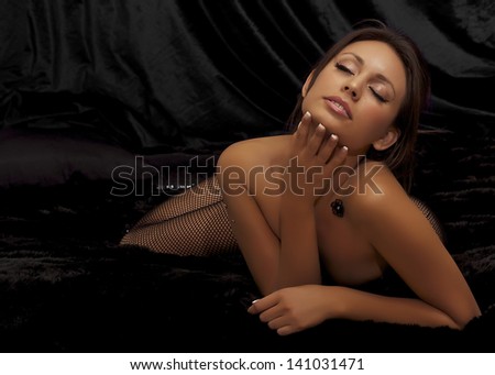 Beautiful actress model in fishnet stockings lying on bed