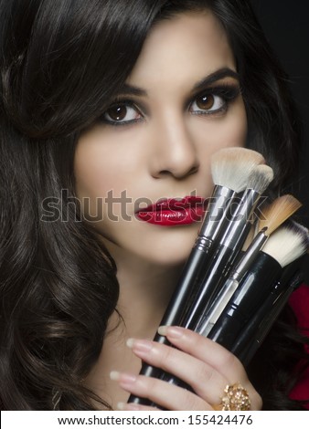 Beautiful elegant woman holding makeup brushes