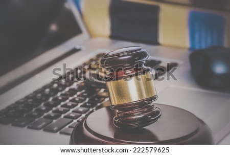 Law legal concept photo of gavel on computer with legal books in background.