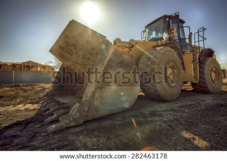 Heavy duty construction digger excavator equipment with sun flare.