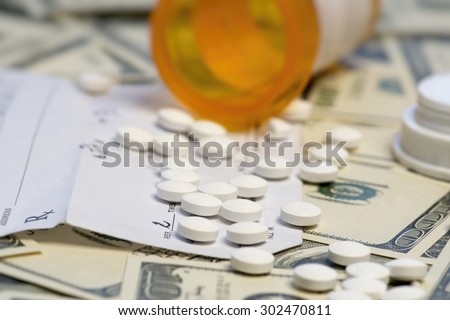 Bottle of prescription pills over dollar bills.