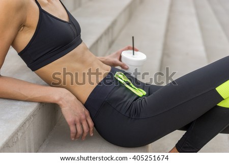 Woman recovering from workout - drinking water - focus on abs stomach