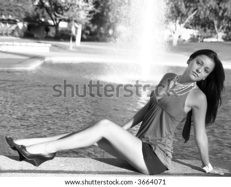 Gorgeous girl lying next to fountain in park, shot in black and white.