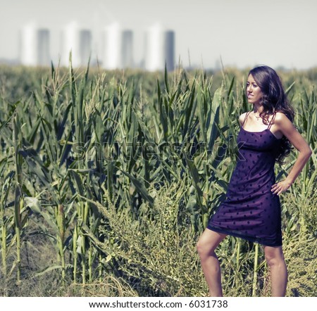 stock photo : Beautiful woman standing alone beside a corn field with silos 