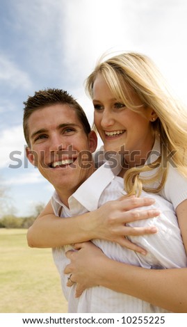 Attractive couple having fun while man gives woman a piggy back ride