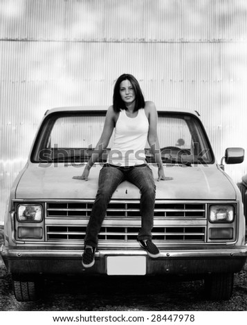 Black and white portrait of a an attractive young woman sitting on car truck