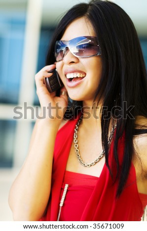 Happy busy young beautiful woman talking on cell phone.