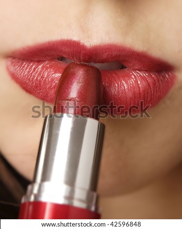 Close up of a female applying red lipstick, white background.