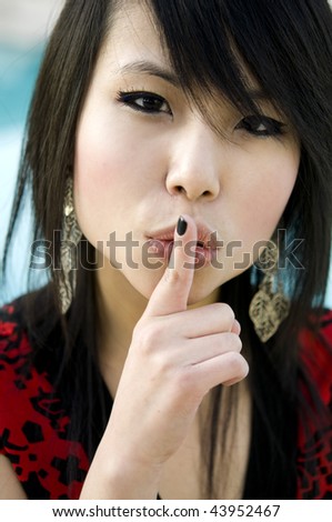 Sshh, Beautiful Asian woman holding finger to mouth gesturing silence.