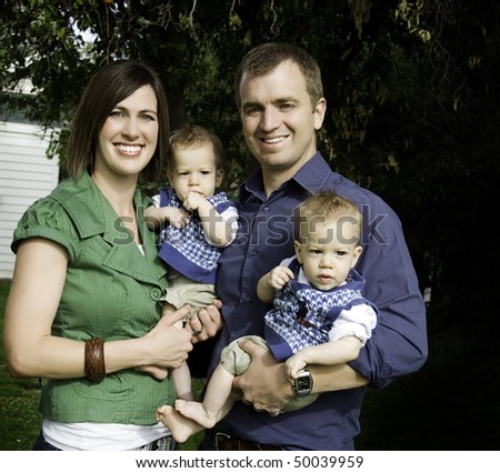 Family shot, husband and wife smiling while holding their twins baby boy identical twinds