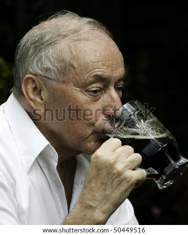 Senior man drinking a beer outside of pub.