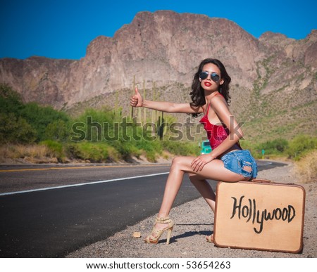 stock photo : Beautiful young Hollywood hopeful hitching a lift on a desert 