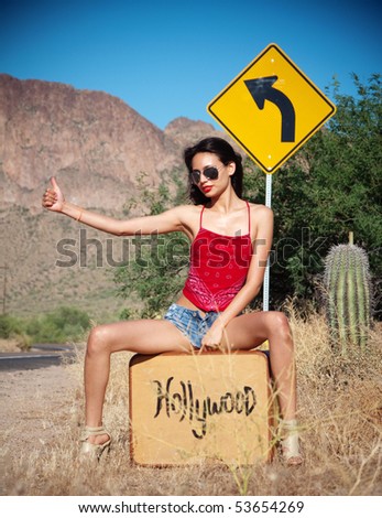 stock photo : Beautiful young woman hitching a lift to Hollywood on a desert road in