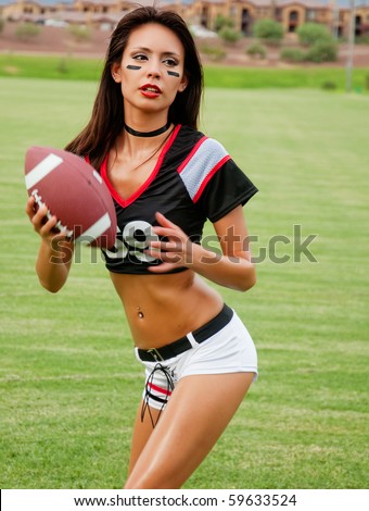 Beautiful young woman wearing American football outfit catching football