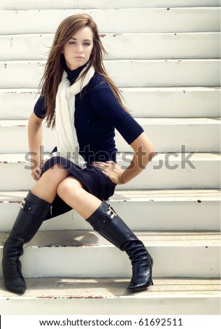 Fashion style portrait of beautiful young woman wearing elegant stylish clothing, pencil skirt, black boots and scarf.