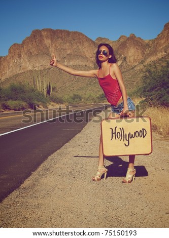 Young woman hitching a ride on lonely desert road