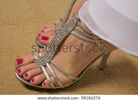 Close up photo of brides pretty feet in beautiful silver shoes with carefully manicured toe nails.