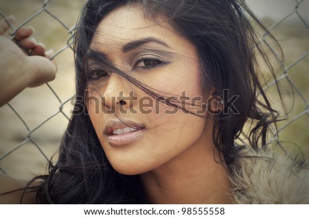 Close up portrait of beautiful young exotic beauty with wind blowing strands of hair across face.