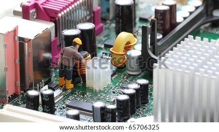 Macro photograph of a computer motherboard and a tiny toy engineer fixing something, concept.