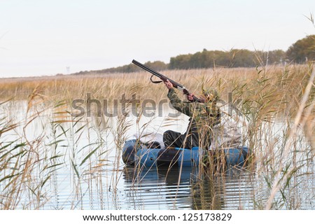 Hunter in an inflatable boat shoots duck