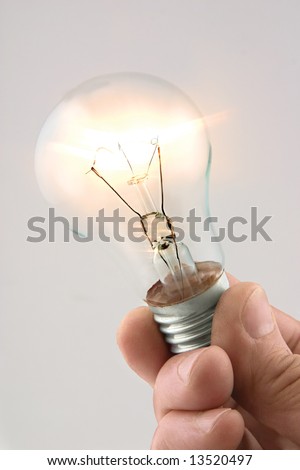 Hand holding burning electric lamp