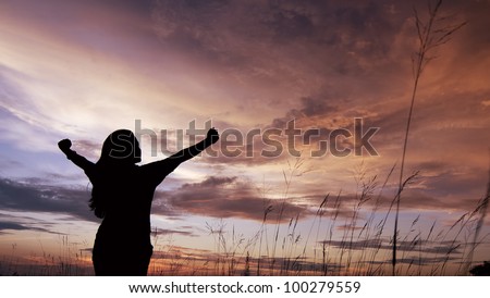 Girl in silhouette with open arms freedom feeling over sunset background