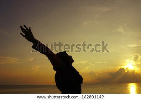 Girl in silhouette with open arms freedom feeling over sunset background
