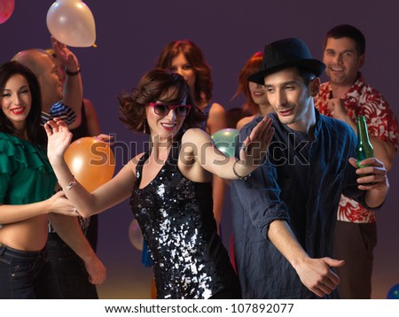 happy, young couple flirting and dancing on the dancefloor in a night club