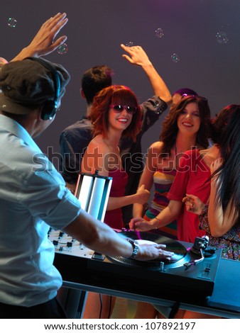 dj entertaining the happy, dancing crowd in a night club