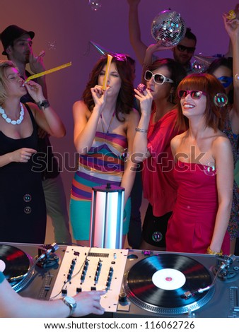 young, beautiful women, dancing at a party and playing  with party horns