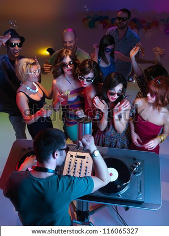 young girls at party, flirting and dancing toghether in front of the turntable, while the dj is mixing, view from above