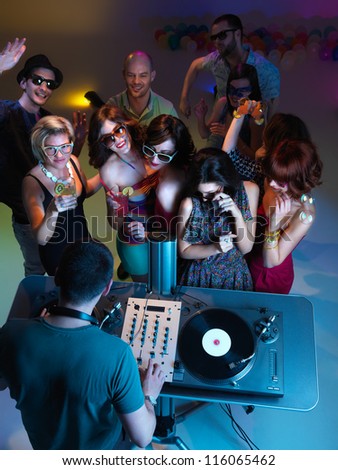 young, beutiful girls smiling and dancing, dj, mixing music, with guys dancing in the background, view from up
