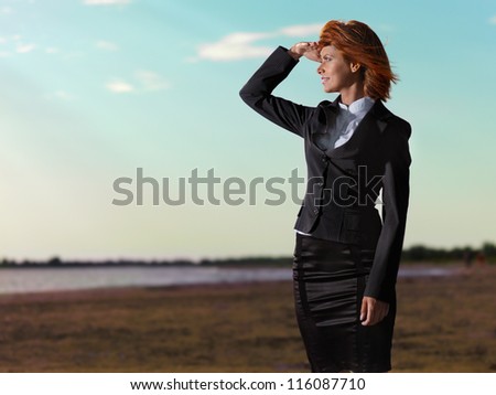 confident, young businesswoman looking at the horizon, on the sea shore