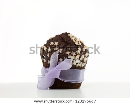 single chocolate muffin, decorated with white sugar stars, wrapped in purple ribbon, on white backround