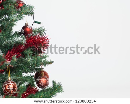 detail of a christmas tree decorated with red garland and globes isolated on white background framed in the left border of the image