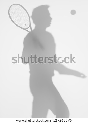 side view of man tennis player at service, behind a diffuse surface