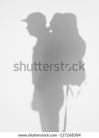 side view of man with backpacker and a cap on his head behind a diffuse surface