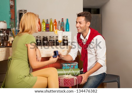 young man giving gifts to young woman in a cafe bar