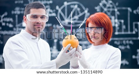 close-up of two scientists in a chemistry lab analyzing chemical reactions on an injected grapefruit