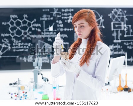 general-view of a student in a chemistry lab injecting mushrooms around a lab table with colorful liquids and a blackboard on the background