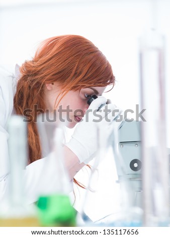 side-view of a student in a chemistry labe analyzing under microscope