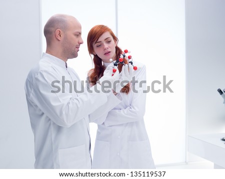 sidel-view  of a student in a chemistry lab curiously observing  a citric acid molecular model holded by her teacher